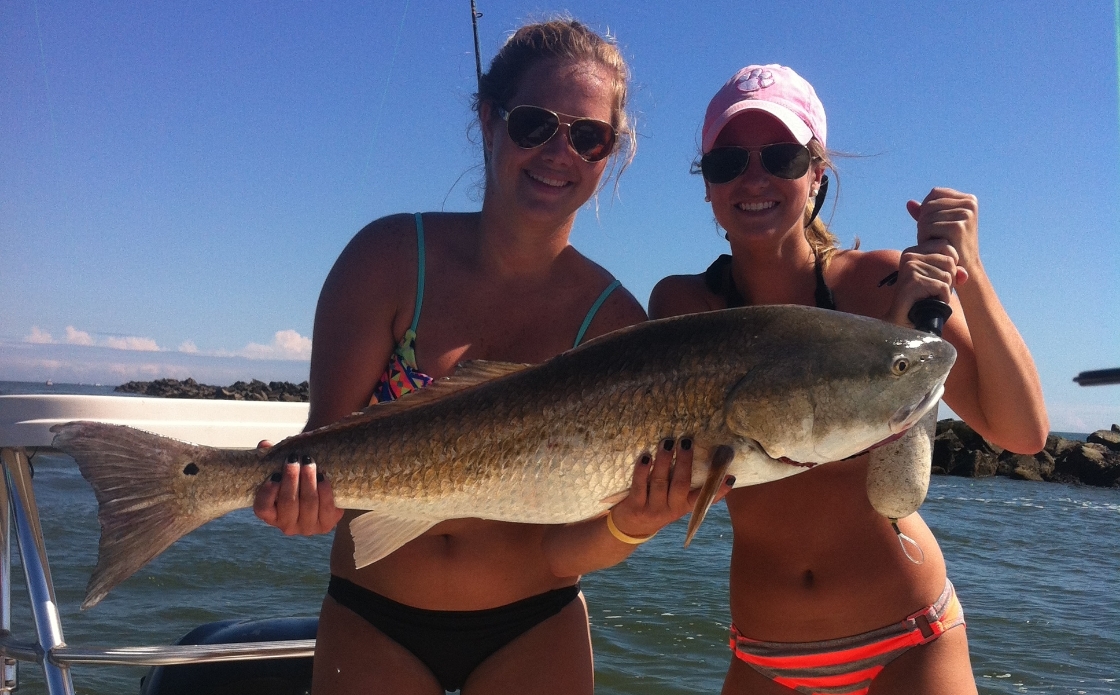 Two ladies pose with a large fish on a fishing charter boat
